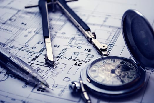 Dividers, pan and pocket watch laying on the architectural project