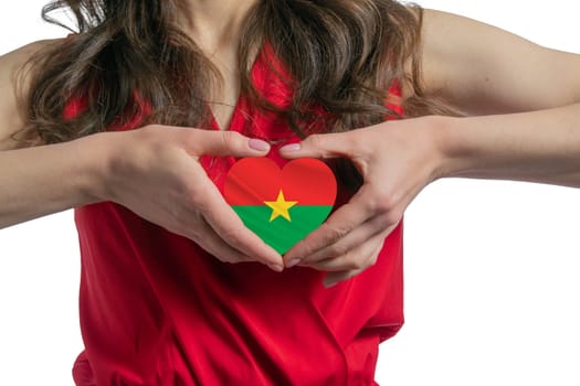 Love Burkina Faso. The woman holds a heart in the form of the flag of Burkina Faso on her chest. Concept of patriotism.