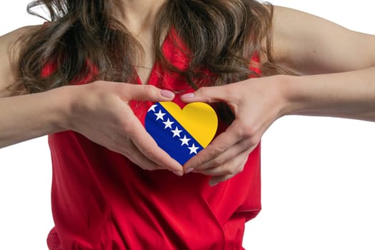 Love Bosnia and Herzegovina. The woman holds a heart in the form of the flag of Bosnia and Herzegovina on her chest. Concept of patriotism.