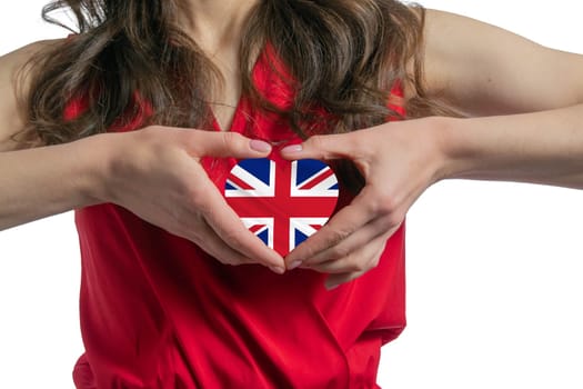 Love United Kingdom. The woman holds a heart in the form of the flag of United Kingdom on her chest. Concept of patriotism.