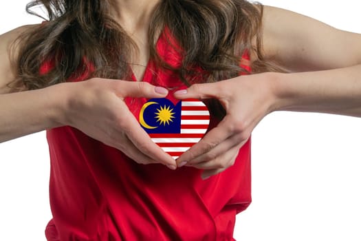 Love Malaysia. The woman holds a heart in the form of the flag of Malaysia on her chest. Concept of patriotism.