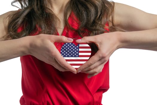 Love United States. The woman holds a heart in the form of the flag of United States on her chest. Concept of patriotism.