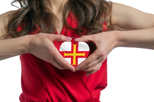 Love Guernsey. The woman holds a heart in the form of the flag of Guernsey on her chest. Concept of patriotism.
