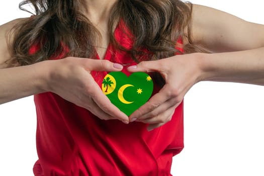 Love Cocos Islands. The woman holds a heart in the form of the flag of Cocos Islands on her chest. Concept of patriotism.