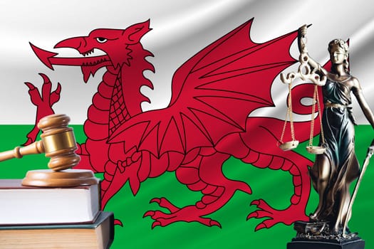 Law and justice in Wales. Statue of themis and the gavel of the judge against the background of the flag of Wales. Law and justice concept.