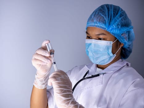 Studio portrait of a female doctor wearing a mask and wearing a hat. In hand was a bottle of vaccine and a sling of syringes. standing on a white background. Studio shot background, COVID-19 concept