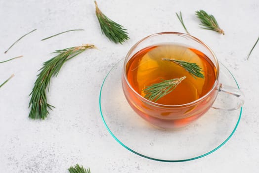 Pine needle tea in a cup on a white textured background, empty copy space for text, hot drink