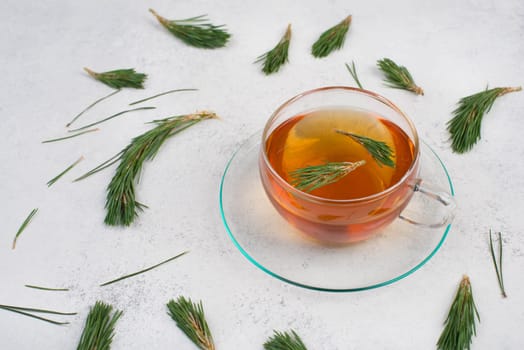 Pine needle tea in a cup on a white textured background, empty copy space for text, hot drink