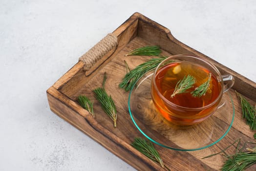 Pine needle tea in a cup on a white textured background, empty copy space for text, hot drink