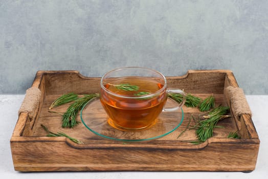 Pine needle tea in a cup on a white textured background, empty copy space for text, hot drink