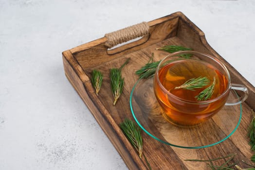 Pine needle tea in a cup on a white textured background, empty copy space for text, hot drink
