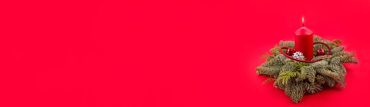 Panorama from red Christmas Candle with green branches over red background