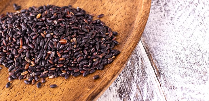 The black rice on old wooden table. Selective focus