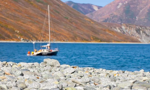 Selective focus. The Pebble beach in the Northern Bay of the Pacific ocean with one boat at anchor as a background. Selective focus