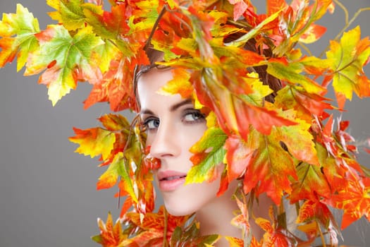 Beautiful young woman wrapped in autumn leafs