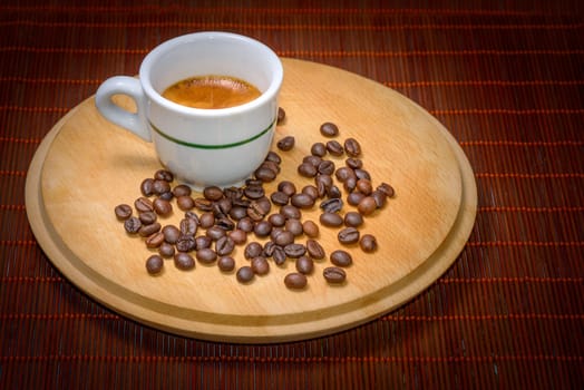 A cup of coffee on wood with seeds around