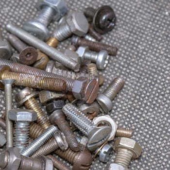 Several old screws on a grey texile background