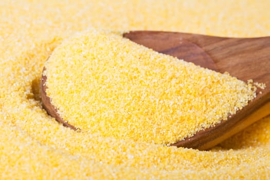 Close up of wooden spoon in raw polenta.
