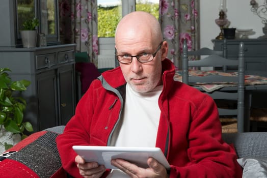 a senior man with a digital tablet on the sofa
