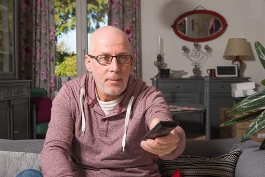 senior on a sofa in his home watch tv