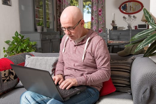 a senior man with a laptop on the sofa