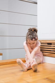 Little girl wearing a ballet dress is practicing ballet in a dance studio