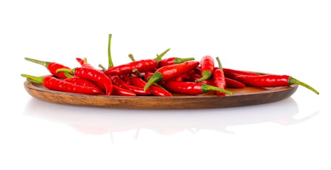The Red hot chili peppers on a wooden plate isolated on white background.