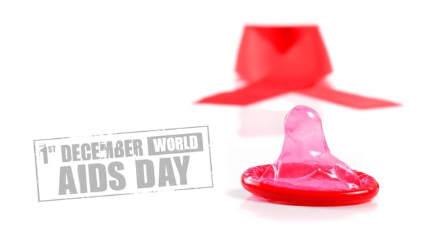 Aids ribbon and condom on white background.