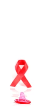 Aids ribbon and condom on white background.
