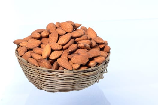 Almonds in a wooden basket with heap isolated on a white background