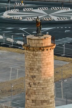 Ancient watchtower with a statue overlooking the sea in Civitavecchia port. A historic maritime structure in a busy harbor. Concept: seafaring heritage