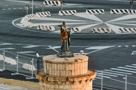 Historic stone tower with a bronze statue on top, located in the port of Civitavecchia. The maritime monument stands among modern infrastructure. Concept: history and navigation