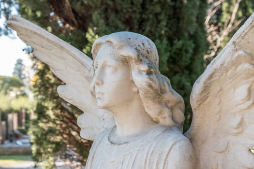 Vintage statue of a sad angel against the background of leaves