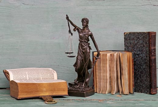 Justice figure and old books on a wooden background. Justice, scales, court