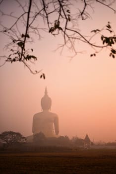 Silhouette big Buddha with the golden sky on the sunset and silhouette of man riding a motorcycle holding bamboo stick afterwork.