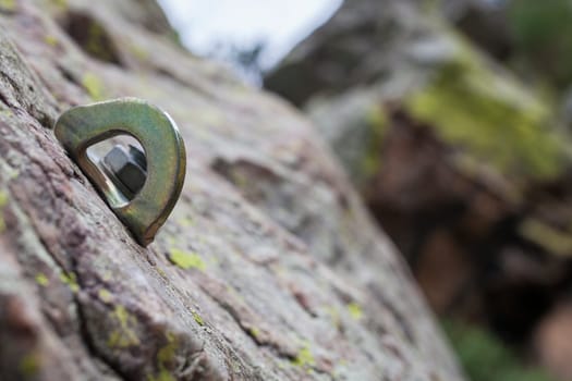 Bolt or parabolt fixed into a hole drilled in the rock full of lichen. Rock-climbing equipment