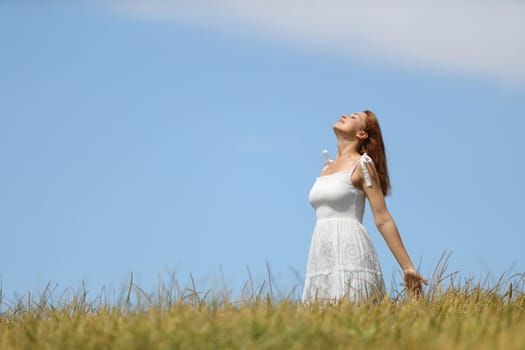 Woman with white dress breathing fresh air in a wheat field