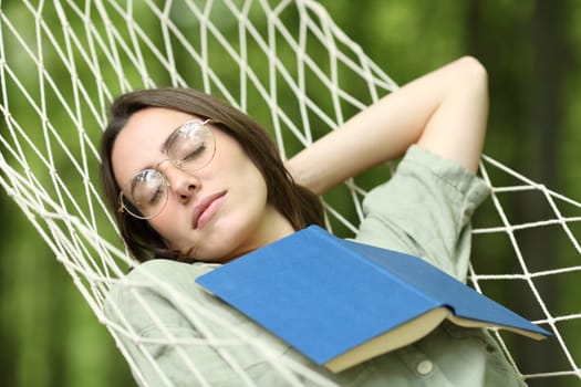 Woman sleeping on hammock with a book