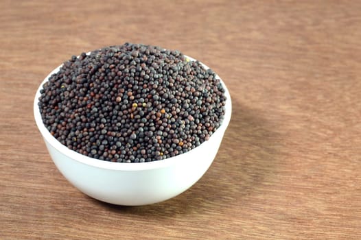 Brown Mustard Seeds in bowl on wooden background