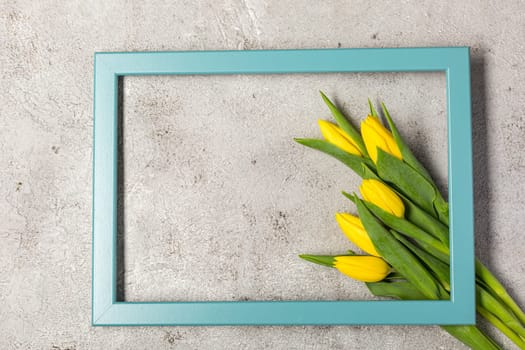 Flat lay with yellow tulips flower and frame on ultimate gray texture. View with copy space. Spring Concept. minimal