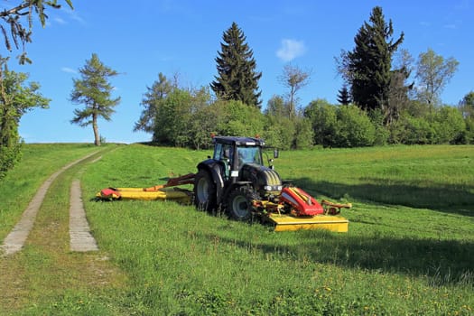 A farmer in Bavaria cuts the grass in a field in summer