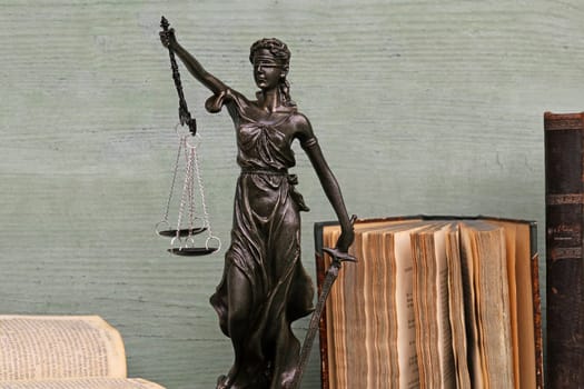 Justice figure and old books on a wooden background. Justice, scales, court