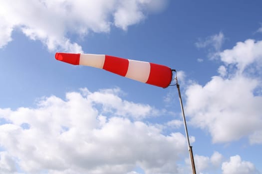 Windsock flag with red and white stripes on blue sky background