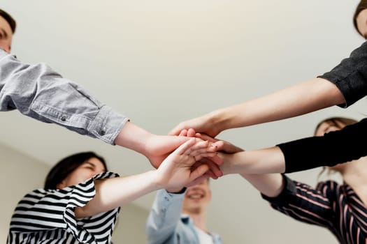 Friendly group of people doing handshake and cross hands. Friendship, agreement, cooperation concept with young teens crossing their hands