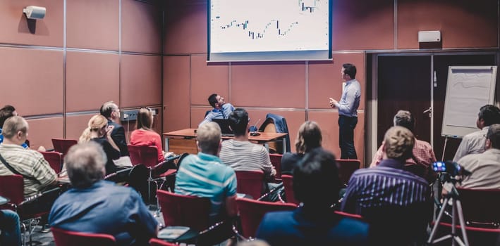 Speaker giving a talk in conference hall at business event. Unrecognizable people in audience at conference hall. Business and Entrepreneurship concept.