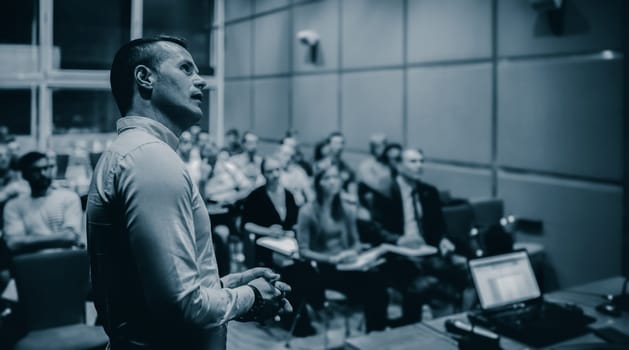 Speaker giving a talk on corporate business conference. Unrecognizable people in audience at conference hall. Business and Entrepreneurship event.