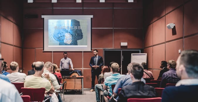 Speaker giving a talk in conference hall at business meeting event. Rear view of unrecognizable people in audience at the conference hall. Business and entrepreneurship concept.