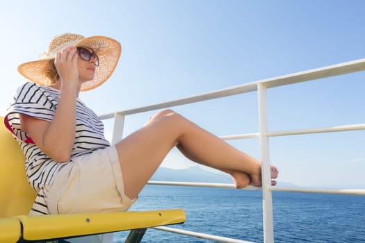 Beautiful, romantic blonde woman relaxeing on summer vacations traveling by cruse ship ferry boat. Summer vacation lifestyle.