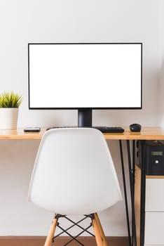 Computer monitor with white blank screen on the business desk with wireless mouse, keyboard at home office over white wall background, Photo of equipment contemporary workspace