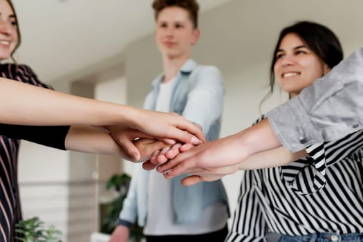 Friendly group of people doing handshake and cross hands. Friendship, agreement, cooperation concept with young teens crossing their hands